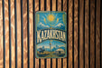 a vintage-style metal sign with the word "Kazakhstan" prominently displayed, set against a wooden background.
