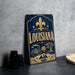 A vintage-style metal sign with the word "LOUISIANA" prominently displayed, featuring a fleur-de-lis symbol and various decorative elements.