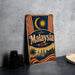 A vintage metal sign with the word "Malaysia" prominently displayed, featuring a crescent moon, sun, and a city skyline.