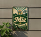 a vintage-style metal sign with a green and gold color scheme, mounted on a wall.