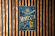 A vintage-style metal sign with the word "MINNESOTA" prominently displayed, featuring a sun, pine trees, and a loon.