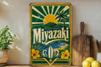 A vintage-style sign for "Miyazaki" is displayed on a shelf, surrounded by various kitchen items such as a potted plant, a cutting board, and a bowl of lemons.
