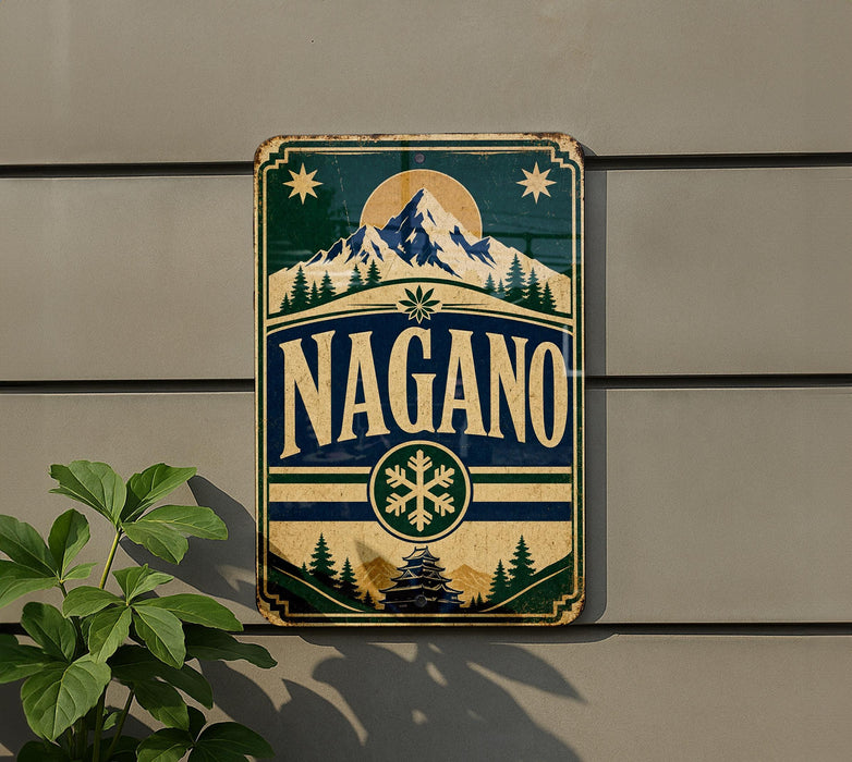 A vintage-style metal sign with the word "NAGANO" prominently displayed, featuring a mountain landscape and snowflake design.