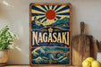 A vintage-style sign for Nagasaki, featuring a sun and waves, with a castle and bridge in the background.