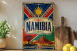a vintage Namibia poster displayed on a shelf, with a wooden cutting board and a potted plant to the side.