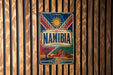 a vintage Namibia poster with a sun and mountain backdrop, hanging on a wooden wall.
