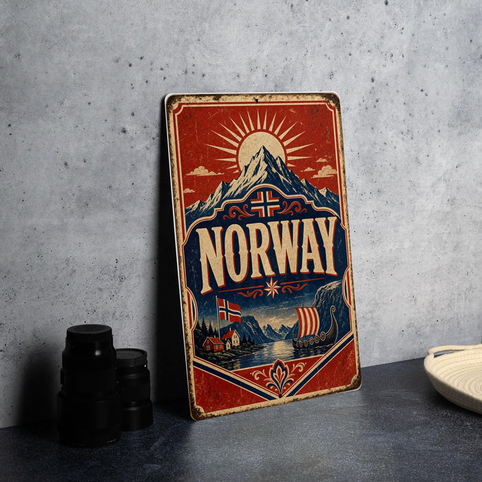 A vintage-style metal sign with the word "NORWAY" prominently displayed, featuring a scenic illustration of mountains, a ship, and a sun.