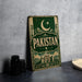 A vintage metal sign with the word "PAKISTAN" prominently displayed, featuring a crescent moon and star symbol, and a castle-like structure in the background.