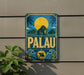 A vintage metal sign with a tropical island landscape and a large yellow sun in the sky, mounted on a wall.