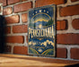 A vintage-style metal sign with the word "PENNSYLVANIA" prominently displayed, featuring a sunburst design and a cityscape illustration.