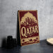 A vintage-style metal sign with the word "Qatar" prominently displayed, featuring a desert landscape and a camel silhouette.