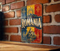 a vintage-style metal sign with the word "ROMANIA" prominently displayed, mounted on a brick wall.