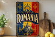 a vintage-style metal sign with the word "ROMANIA" prominently displayed, surrounded by a colorful border with a castle illustration. The sign is placed on a shelf next to a potted plant and a wooden cutting board, creating a rustic and charming atmosphere.