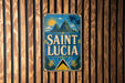 A vintage-style sign for Saint Lucia, featuring a tropical landscape with palm trees and mountains, is displayed on a wooden wall.