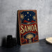 a vintage-style sign with the word "SAMOA" prominently displayed, along with a tropical landscape and stars. The sign is placed on a gray surface, and there are some black objects, such as a stack of cups, to the left of the sign.