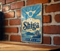 A vintage-style metal sign with the word "Shiga" prominently displayed, mounted on a brick wall.