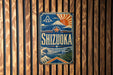 A vintage-style sign for Shizuoka, a famous Japanese city, is displayed on a wooden wall.