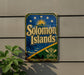 A vintage-style sign for the Solomon Islands, featuring a blue background with a sun and palm trees, and the text "Solomon Islands" prominently displayed.