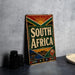 A vintage-style sign with the text "SOUTH AFRICA" prominently displayed, featuring a colorful design with sun and floral elements.