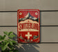 a vintage-style sign with the word "SWITZERLAND" prominently displayed, along with a mountain and other scenic elements.