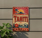 A vintage-style sign for Tahiti, featuring a tropical landscape with palm trees, a sun, and a mountain.