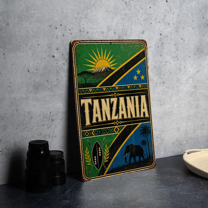A vintage-style metal sign with the word "TANZANIA" prominently displayed, featuring a sun, mountain, and other African-inspired elements.