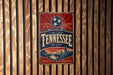 A vintage-style metal sign with the word "TENNESSEE" prominently displayed, featuring a red background with a blue border and a white star above the text.
