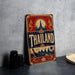 A vintage-style metal sign with the word "Thailand" prominently displayed, featuring a temple and other traditional Thai imagery.