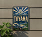 A vintage-style sign for Toyama, featuring a mountain landscape and a wave, is displayed on a wall.