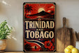 A vintage-style sign with the text "TRINIDAD AND TOBAGO" displayed prominently, featuring a tropical landscape with palm trees, a mountain, and a sun. The sign is placed on a shelf next to a wooden cutting board and a potted plant.