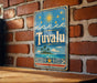 A vintage-style sign with the word "Tuvalu" displayed on a brick wall.
