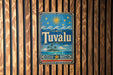 A vintage-style metal sign with the word "Tuvalu" displayed prominently, featuring a tropical island landscape with palm trees and a sun in the sky.