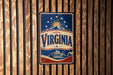 A vintage-style metal sign with the word "VIRGINIA" prominently displayed, featuring a sun and stars design.