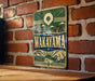 A vintage metal sign with the name "Wakayama" displayed prominently, mounted on a brick wall.