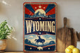 A vintage-style sign for Wyoming featuring a cowboy on a horse, mountains, and a sunburst design.
