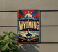 A vintage-style sign for Wyoming mounted on a wall, featuring a cowboy silhouette and a mountain landscape.