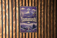 A vintage-style sign for Yamanashi, featuring a mountain landscape and a temple, is displayed on a wooden wall.