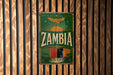a vintage-style sign with the word "Zambia" prominently displayed, mounted on a wooden wall.