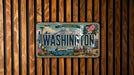 A vintage Washington state license plate is displayed against a wooden background.