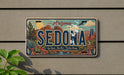 A vintage Arizona license plate with a scenic desert landscape design, mounted on a wall.