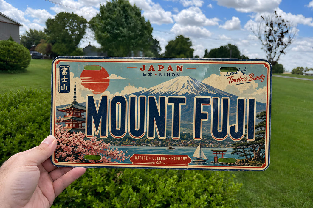 A person is holding a framed license plate with the word "MOUNT FUJI" on it, which is a Japanese license plate. The plate features a scenic image of Mount Fuji and other Japanese landmarks.