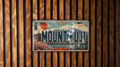 A vintage license plate with the text "MOUNT FUJI" is displayed against a wooden background.