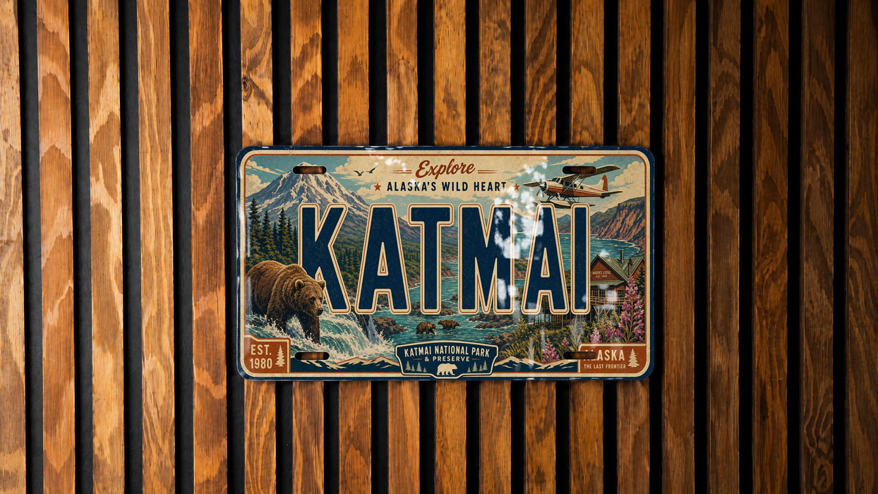 A vintage-style license plate with the text "KATMAI" and an illustration of a bear, mountains, and a plane, mounted on a wooden wall.