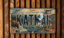 A vintage license plate with a scenic mountain landscape and a bear, featuring the text "KATMAI" prominently displayed.