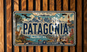 A vintage license plate from Patagonia, featuring a scenic mountain landscape with a lighthouse, llama, and other wildlife.
