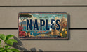 A vintage license plate from Italy that says "NAPLES" and features an illustration of a cityscape with a dome and palm trees.