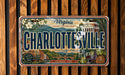 A Virginia license plate with the text "CHARLOTTE'SVILLE" and an illustration of a cityscape with buildings, trees, and a bridge.