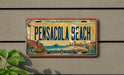 A license plate from Pensacola Beach, Florida, with a vintage design depicting the beach and surrounding area.