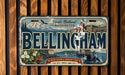 A vintage license plate from Washington, featuring the city of Bellingham and its surrounding natural and community landmarks.