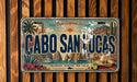 A vintage license plate from Cabo San Lucas, featuring a colorful illustration of the city's landmarks and a sombrero.